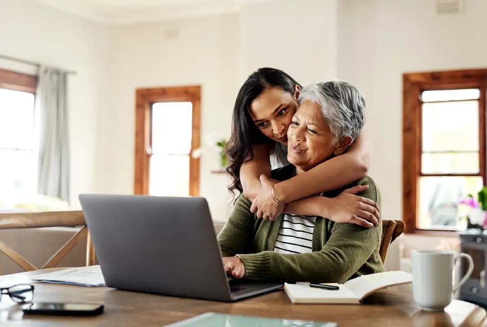 a senior woman being hugged by her adult daughter