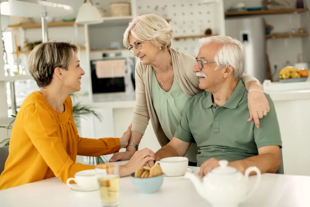 a woman sitting in the kitchen with her senior parents with dementia