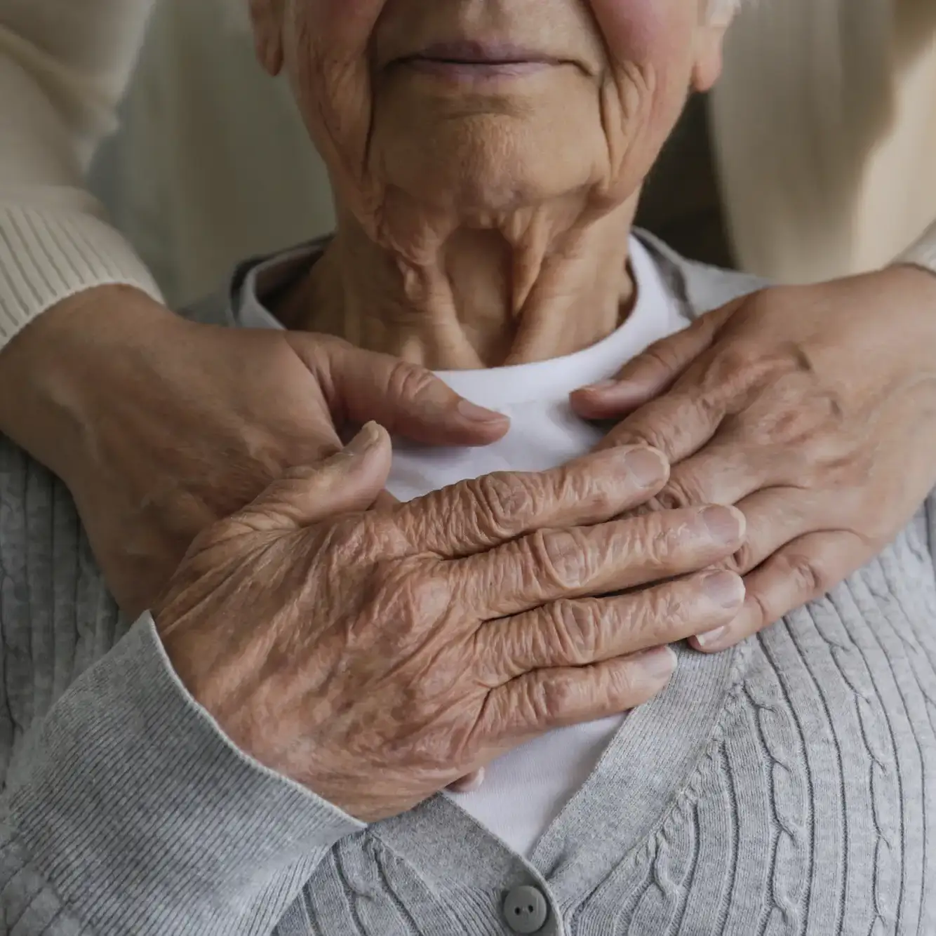 iStock-1397723552-square close-up of a senior woman's hands clasping those of her caregiver
